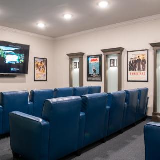 A cozy home theater with blue seating and movie posters on the walls.