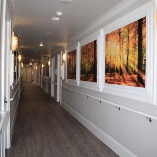 A well-lit hallway with autumn-themed artwork on the walls and wooden flooring.
