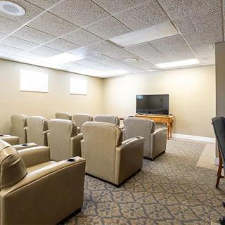 A modern home theater room with comfortable seating and a large television.