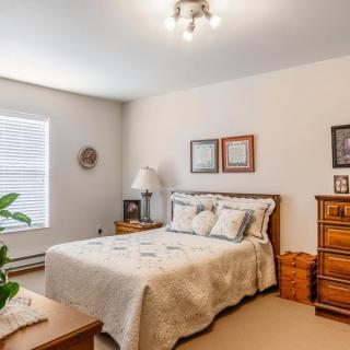 A cozy bedroom featuring a comfortable bed, wooden dresser, and a window allowing natural light.