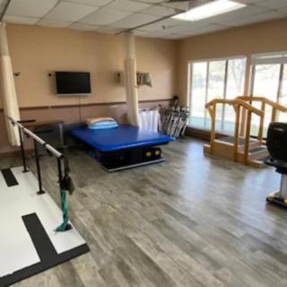 A rehabilitation room equipped with parallel bars, a therapy bed, and other exercise equipment.