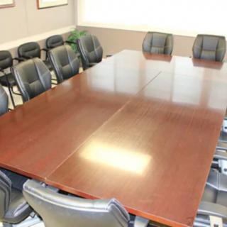 An empty conference room with a large wooden table and surrounding chairs.