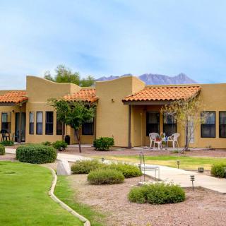 A southwestern-style house with a patio set against a backdrop of mountains and desert landscaping.