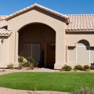 A suburban house with a well-maintained lawn and desert landscaping.