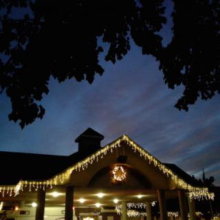 A cozy evening scene with holiday lights adorning a building under a twilight sky.