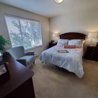 A cozy bedroom with a neatly made bed, bedside tables, and a large window.
