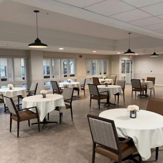 A modern dining area featuring neatly arranged tables and chairs, illuminated by stylish pendant lights.