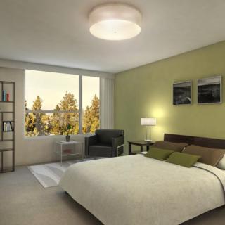 A modern bedroom with a large bed, cozy armchair, and ample natural light from the window.