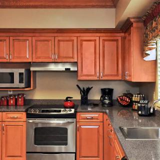 A cozy kitchen with wooden cabinets, a stovetop, and various appliances.