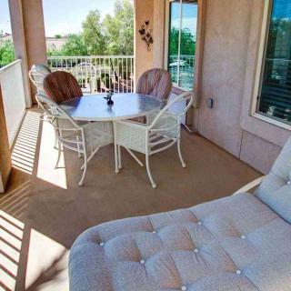 A sunny balcony with a table, chairs, and a comfortable lounger.