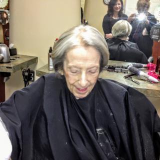 An elderly person in a hair salon getting their hair styled.