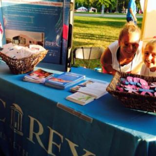 An outdoor event with an information booth displaying brochures and baskets on a table.