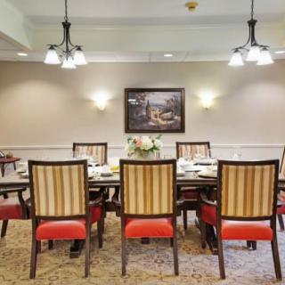 A well-appointed dining room with a large table, elegantly upholstered chairs, and warm lighting.