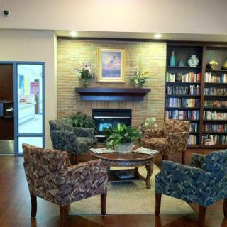 A cozy library with a fireplace, surrounded by bookshelves and comfortable seating.
