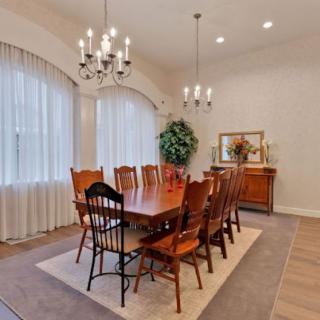 Elegant dining room with a large wooden table and chandelier lighting.