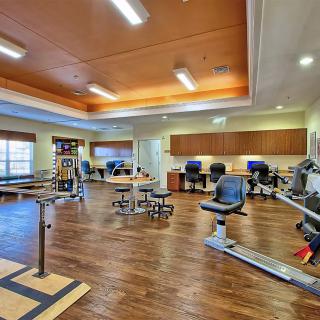 A spacious rehabilitation and therapy room equipped with exercise machines and furniture designed for physical therapy sessions.