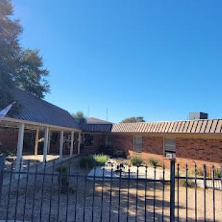 A sunny backyard view featuring a fenced area and a pool.