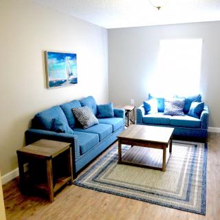 A cozy living room with blue sofas, a wooden coffee table, and wall art.