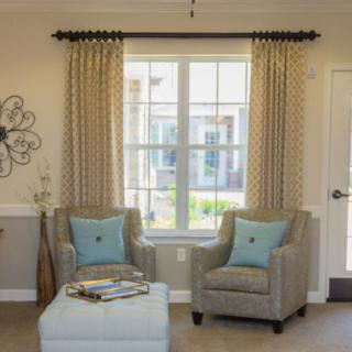 A cozy living room setup with two armchairs, a window adorned with curtains, and a small table.