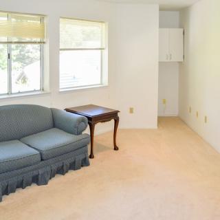 A simple living room with a blue couch, side table, and carpeted floor.