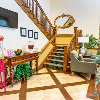 A cozy interior featuring a stylish staircase with wooden railings, comfortable seating, and decorative elements like a large mirror and plants.
