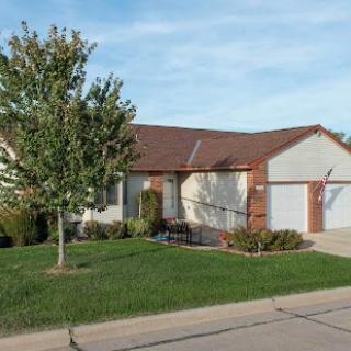 A charming single-story house with a well-maintained front yard and a tree.