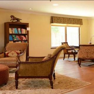 A cozy living room with elegant furniture, a bookshelf, and a large window allowing natural light in.