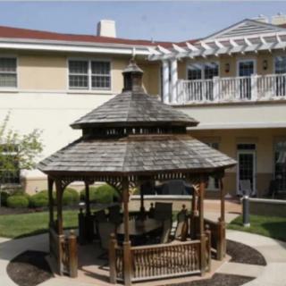 A wooden gazebo situated in a courtyard surrounded by buildings.