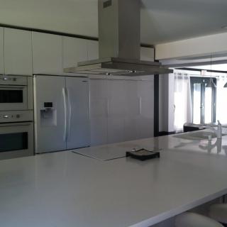 A modern kitchen with white cabinetry, a large refrigerator, and a central island.