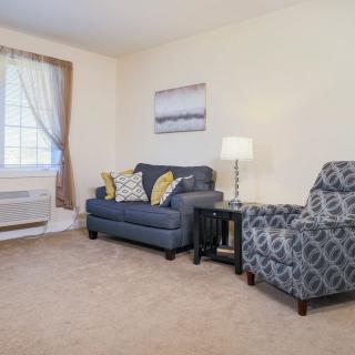 A cozy living room with a sofa, armchair, and lamp.