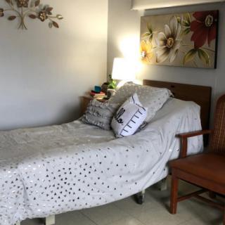 A cozy bedroom with a single bed, decorative pillows, and artwork on the wall.