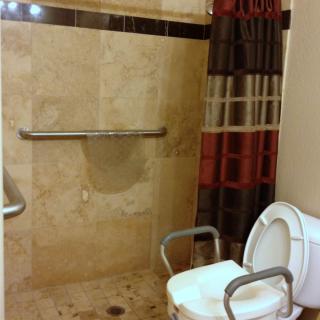 Accessible bathroom with a shower, grab bar, and toilet.