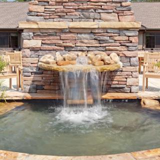 A serene waterfall cascading over a stone fountain, creating a peaceful outdoor atmosphere.