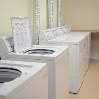 A laundry room featuring multiple washing machines lined up along the wall.