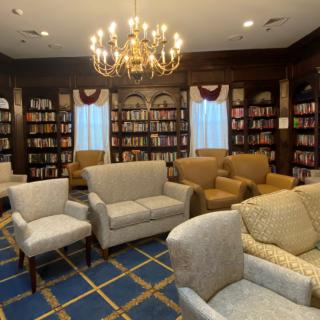 A cozy library with comfortable seating and a chandelier.