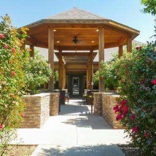 A beautifully landscaped pathway leads to a wooden gazebo surrounded by vibrant flowers.