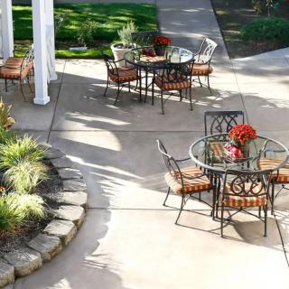 A well-maintained patio area with outdoor tables and chairs set amid landscaped gardens.