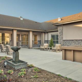 A modern courtyard featuring outdoor seating and a central fountain.