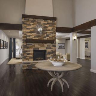 A modern living room featuring a stone fireplace and a round table on dark wood flooring.