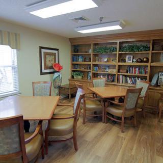 A cozy library room with bookshelves and multiple tables and chairs for reading.
