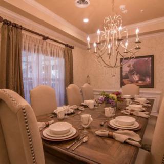 An elegantly set dining room with a chandelier and complete table settings.