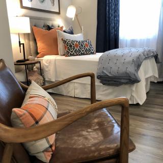 A cozy bedroom with a comfortable chair, stylish bed, and soft lighting.