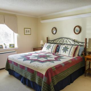 A cozy bedroom with a large bed covered in a patchwork quilt, featuring traditional decor and soft lighting.