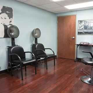 A cozy hair salon with drying chairs and a stylish poster on the wall.
