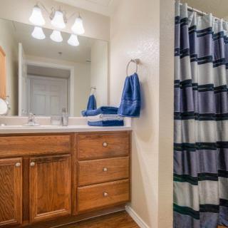 A bathroom featuring a wooden vanity with a mirror, blue towels, and a striped shower curtain.