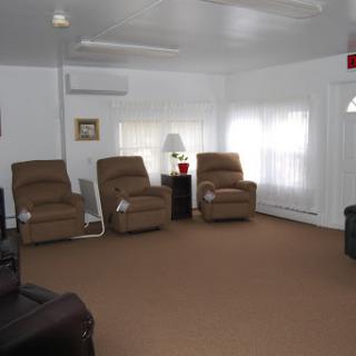 A cozy living room featuring comfortable recliners, a lamp, and ample natural light.