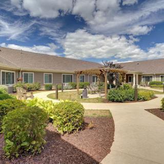 A serene residential building surrounded by landscaped gardens and a clear blue sky.