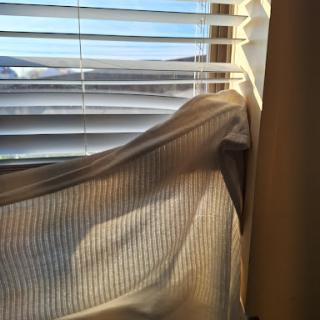 Sunlight filtering through blinds and a curtain, creating a warm glow in the room.