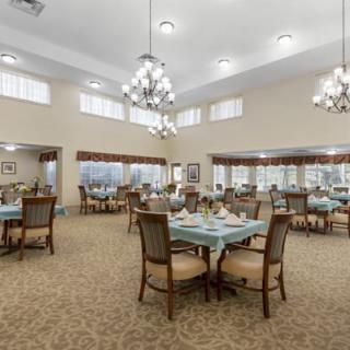 A spacious and elegantly decorated dining room with multiple tables and chandeliers.