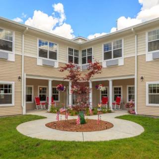 A residential building with a landscaped courtyard featuring a central tree and surrounding seating.
